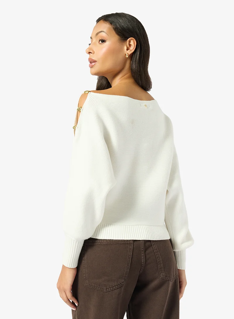 جس كنزة صوفية بأكمام طويلة وكتف مكشوف مزينة بالخرز